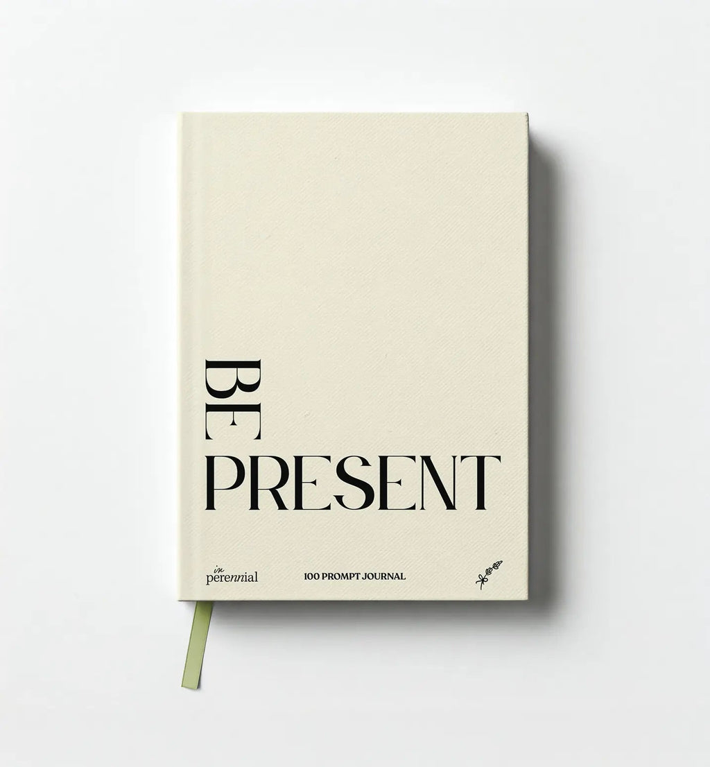 Front cover of in Perennial's beige Be Present 100 Prompt Journal, with black lettering and a green ribbon bookmark.