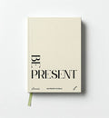 Front cover of in Perennial's beige Be Present 100 Prompt Journal, with black lettering and a green ribbon bookmark.